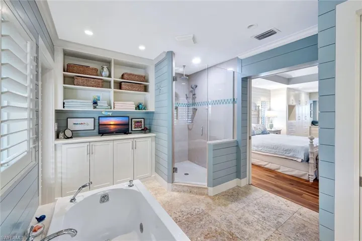Ensuite bathroom featuring a shower stall, a tub with jets, ornamental molding, and tile patterned flooring