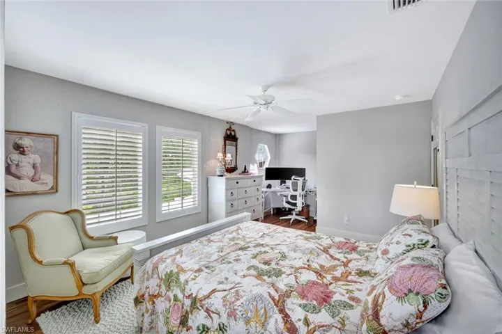 Bedroom with ceiling fan, wood finished floors, and a desk