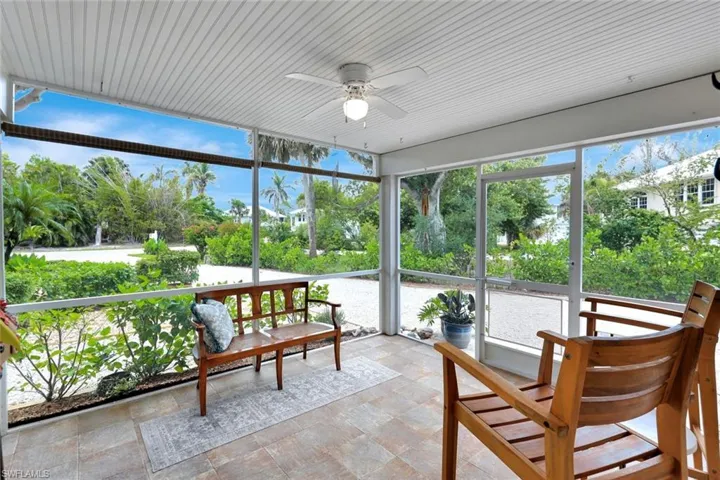 Sunroom with ceiling fan, plenty of natural light, and view of scattered trees