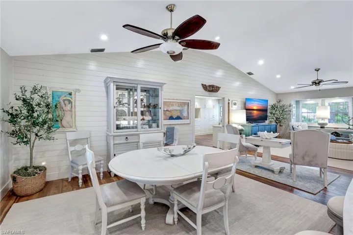 Dining space with ceiling fan, lofted ceiling, wood finished floors, wood walls, and recessed lighting