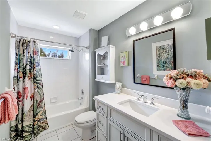 Bathroom with vanity, shower / bath combination with curtain, and tile patterned floors