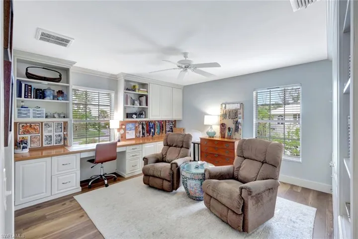 Office space featuring built in desk, healthy amount of natural light, a ceiling fan, and light wood finished floors