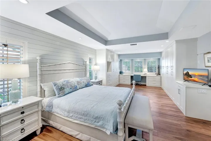 Bedroom with wood finished floors, a tray ceiling, a desk, and recessed lighting