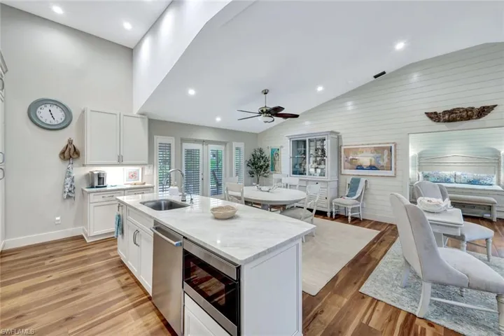 Kitchen with open floor plan, appliances with stainless steel finishes, an island with sink, white cabinetry, and a ceiling fan