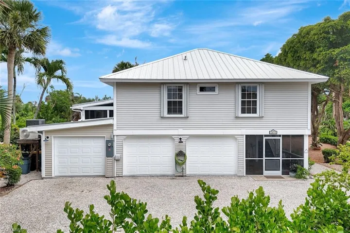 Back of property featuring driveway, a garage, and a sunroom