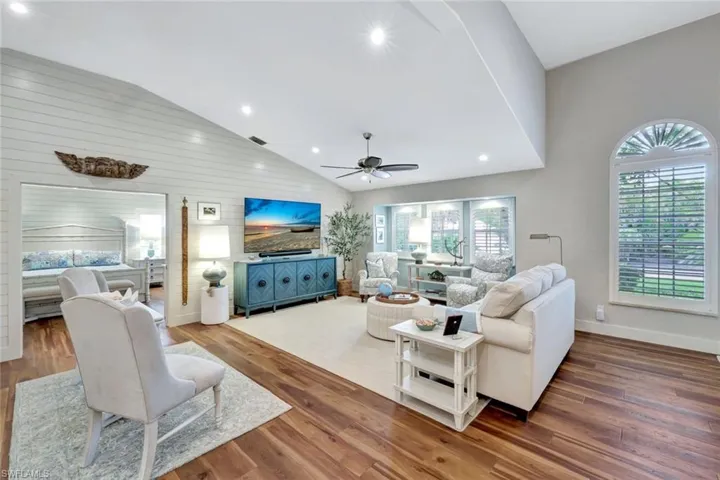 Living room with ceiling fan, high vaulted ceiling, wood finished floors, wood walls, and recessed lighting