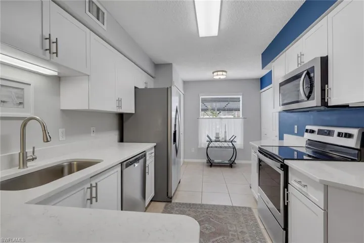 Remodeled with quartz countertops; pantry is just past the refrigerator and doors to the right are to the washer and dryer