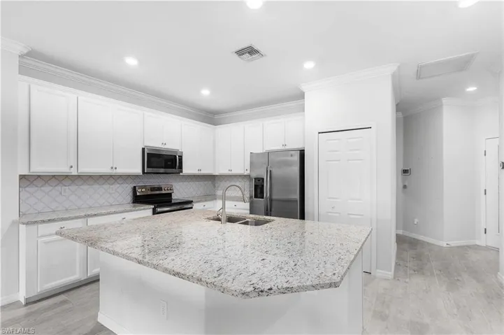 Kitchen featuring stainless steel appliances, white cabinetry, and sink