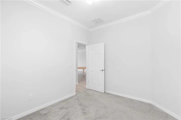 Empty room featuring ornamental molding and light carpet