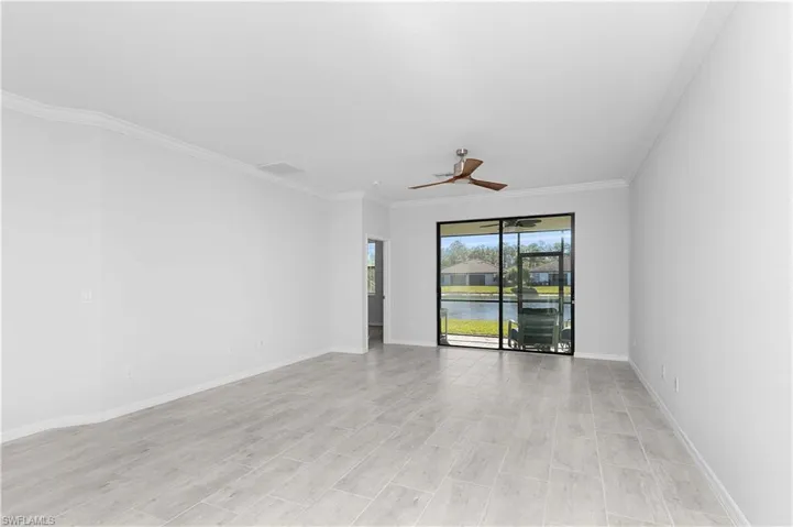 Empty room featuring crown molding, ceiling fan, and a water view