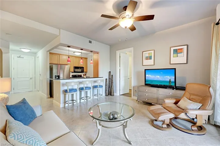 Living area with a ceiling fan and light tile patterned flooring