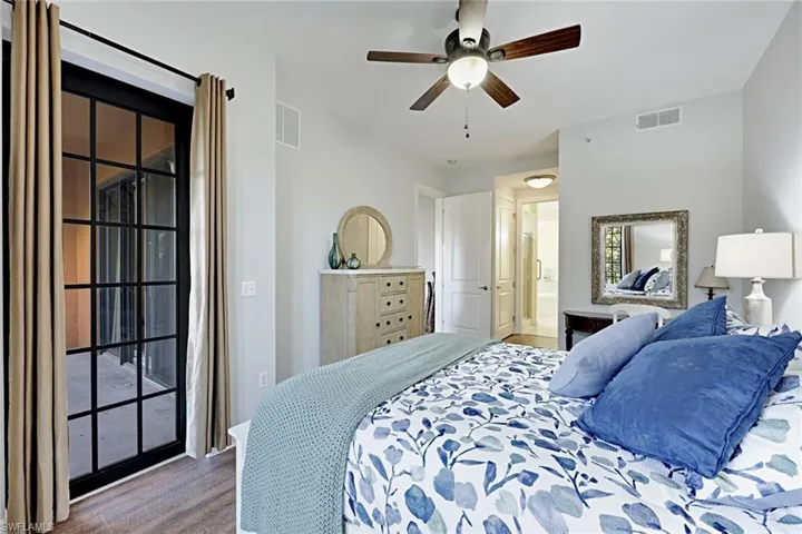 Bedroom with wood finished floors, ceiling fan, access to exterior, and connected bathroom