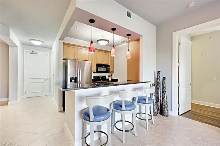 Kitchen featuring black appliances, light tile patterned flooring, a breakfast bar, and a peninsula