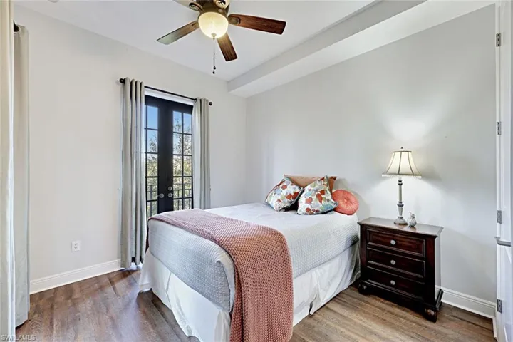 Bedroom with dark wood-type flooring, a ceiling fan, and access to exterior