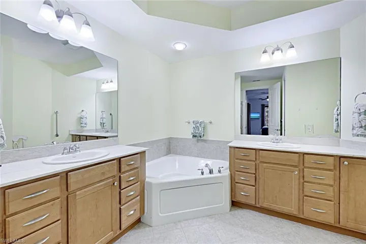 Bathroom with a bath, two vanities, and light tile patterned floors