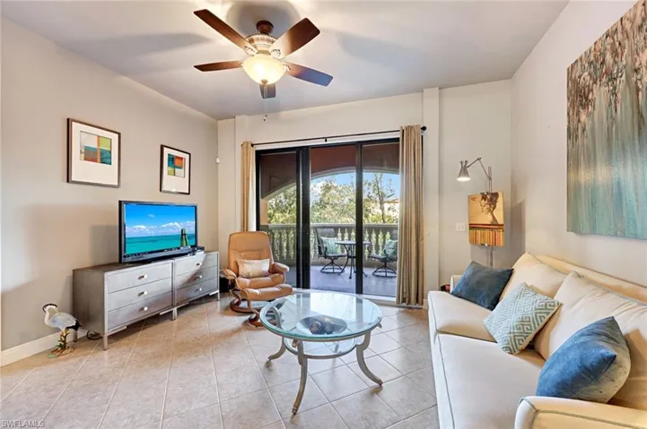 Tiled living area featuring ceiling fan and baseboards