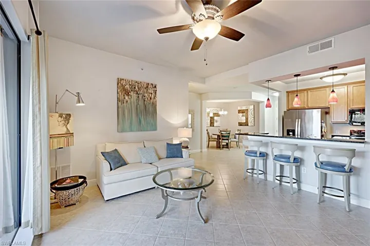 Living room with light tile patterned flooring, ceiling fan, and a chandelier