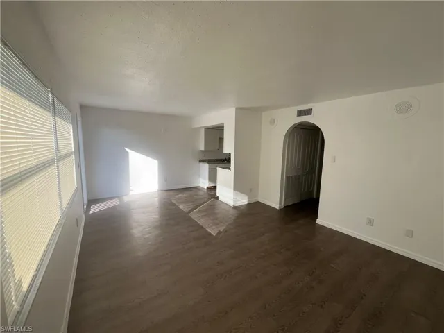 Spare room with dark wood-style floors, arched walkways, and a textured ceiling