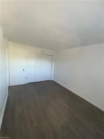 Unfurnished bedroom featuring dark wood-style flooring and a closet
