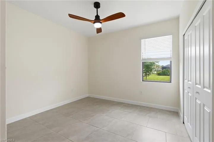 Neutral-toned room featuring large format tile flooring and a ceiling fan with integrated lighting