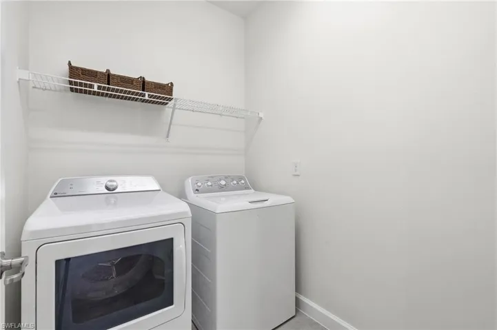 Dedicated laundry area featuring a wire storage shelf, light gray wall paint, and white baseboards