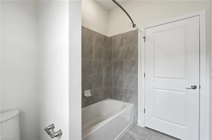 Bathroom featuring a white bathtub, gray tile surround, and coordinating gray tile flooring