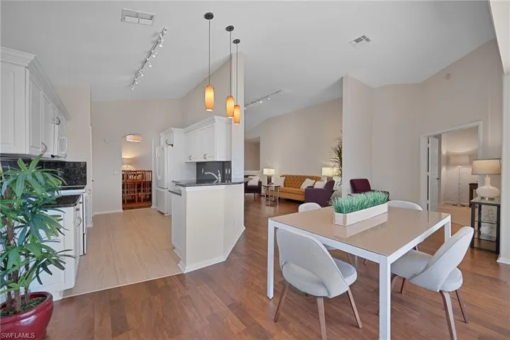 Dining area featuring track lighting, light wood-type flooring, and high vaulted ceiling