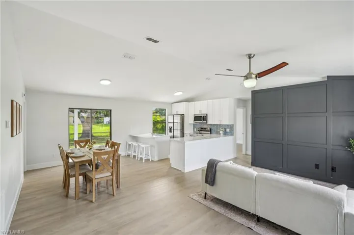 Living room featuring lofted ceiling, ceiling fan, baseboards, light wood-type flooring, and recessed lighting