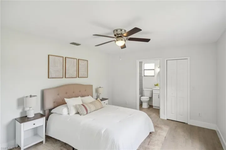 Bedroom featuring light wood-style flooring, ensuite bath, ceiling fan, and baseboards