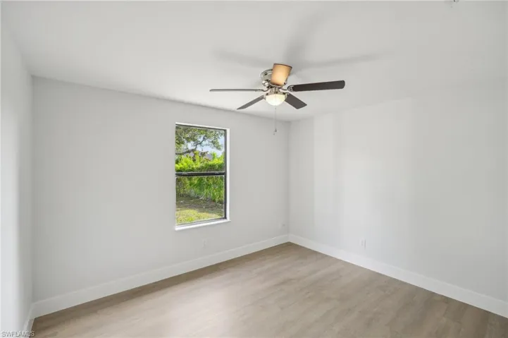 Spare room featuring baseboards, ceiling fan, and light wood-type flooring