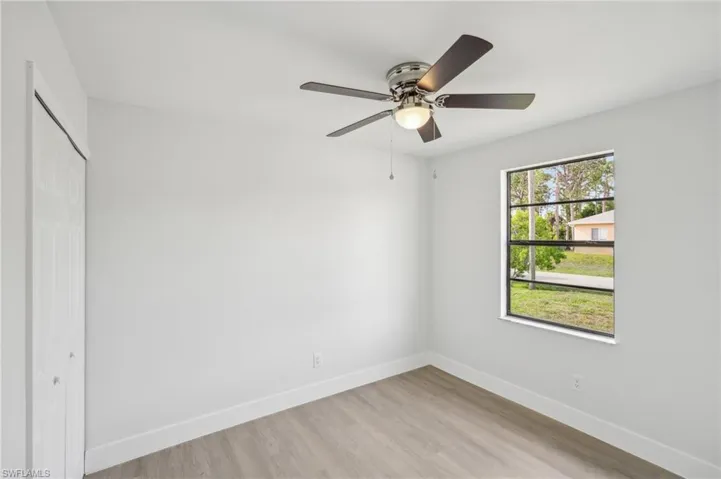 Unfurnished bedroom featuring baseboards, a closet, light wood-style flooring, and a ceiling fan