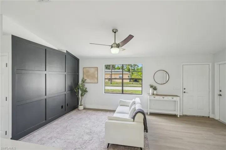 Living area with a ceiling fan, light wood-type flooring, lofted ceiling, and baseboards