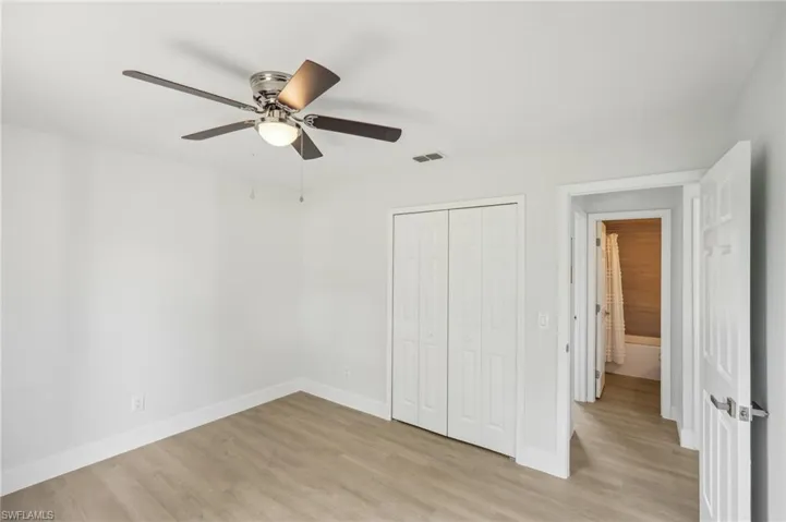 Unfurnished bedroom with light wood-style flooring, a closet, baseboards, and ceiling fan