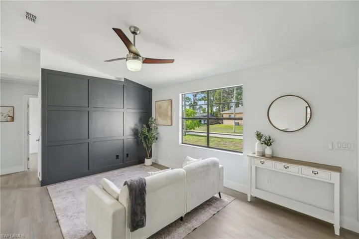 Living room with ceiling fan, wood finished floors, vaulted ceiling, and baseboards
