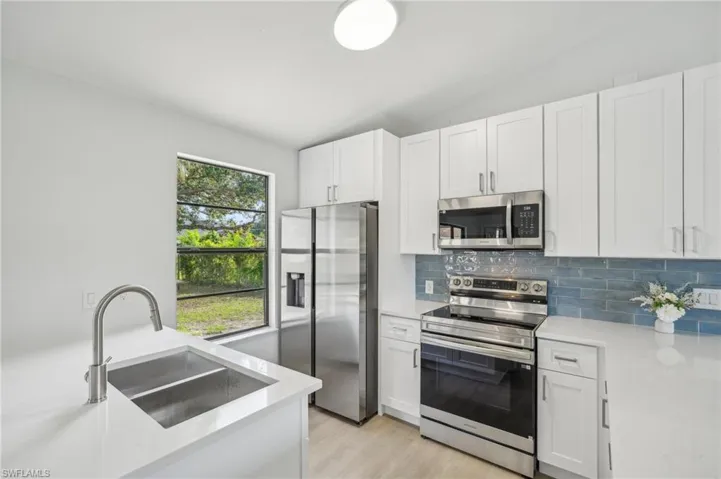Kitchen with stainless steel appliances, a sink, light countertops, tasteful backsplash, and lofted ceiling