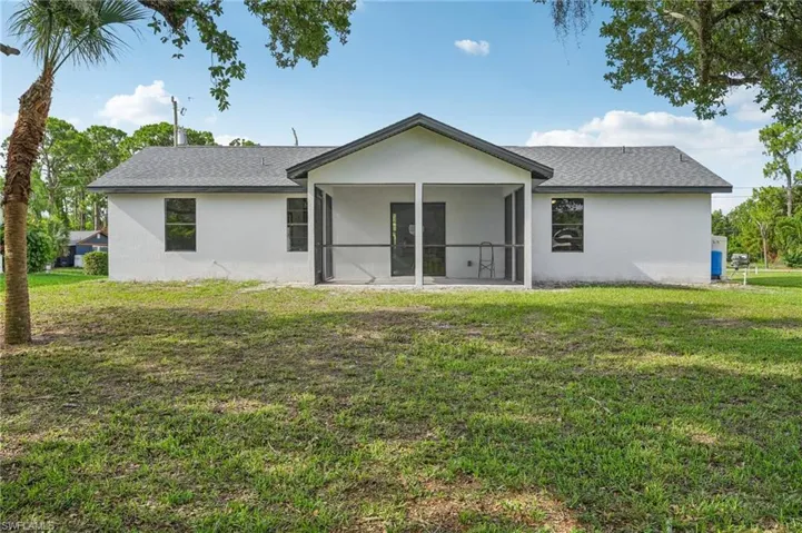 Back of property with stucco siding, a yard, and a sunroom