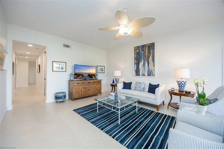 Living room with ceiling fan and light tile patterned flooring
