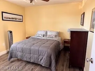 Bedroom with a ceiling fan and dark wood-type flooring