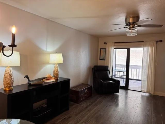 Living area featuring dark wood-style flooring, a ceiling fan, and a textured ceiling