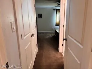 Hallway featuring dark carpet