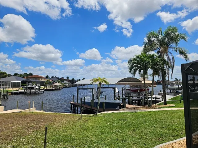 Dock area featuring a water view, a lawn, and boat lift