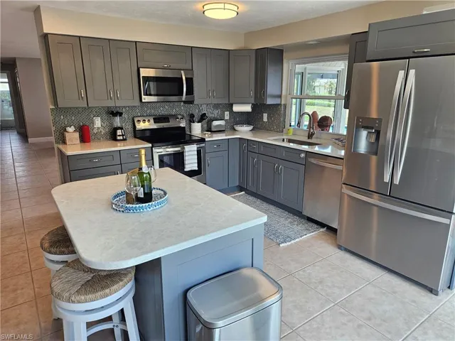 Kitchen featuring a sink, light countertops, decorative backsplash, and appliances with stainless steel finishes