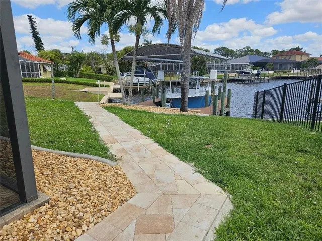 Dock area featuring boat lift, a water view, and a lawn