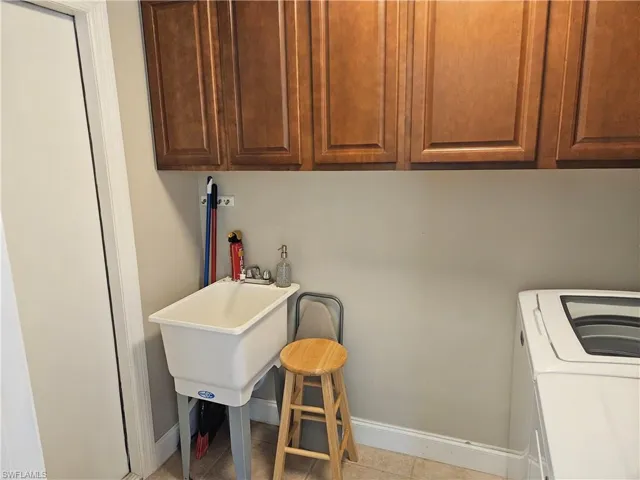 Laundry area featuring baseboards, cabinet space, washing machine and dryer, and tile patterned flooring