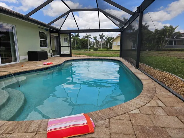 Outdoor pool featuring a lawn, glass enclosure, and a patio area