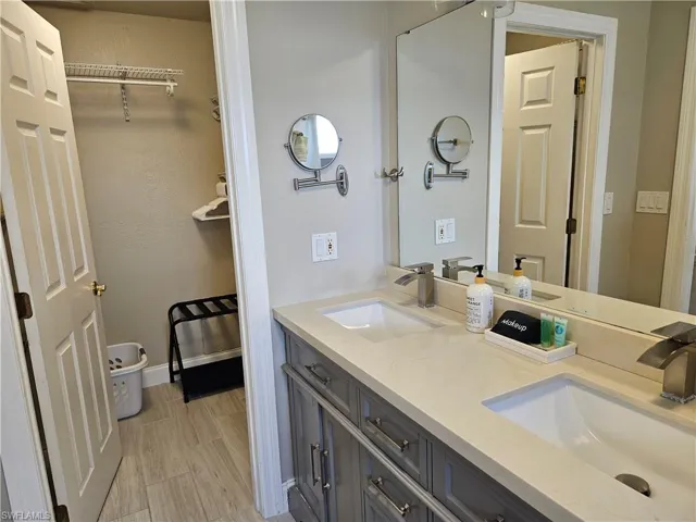 Bathroom featuring baseboards, double vanity, a sink, and wood finished floors