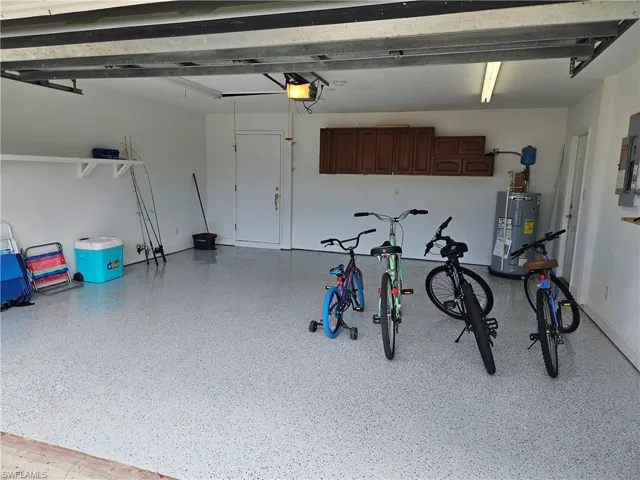 Garage featuring water heater, electric panel, and a garage door opener