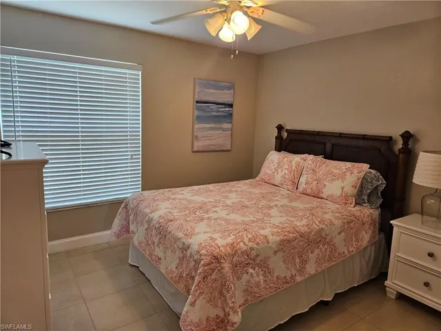 Bedroom featuring light tile patterned flooring, baseboards, and ceiling fan