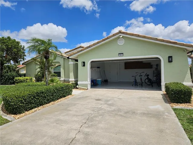 View of front facade featuring a tile roof, concrete driveway, stucco siding, and an attached garage