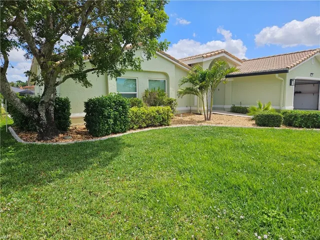 View of front of house with a tiled roof, a front yard, an attached garage, and stucco siding